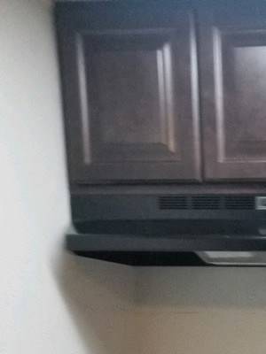 Kitchen with hardwood like flooring, a black stove, stainless steal sink, white countertops, and dark brown cabinets.